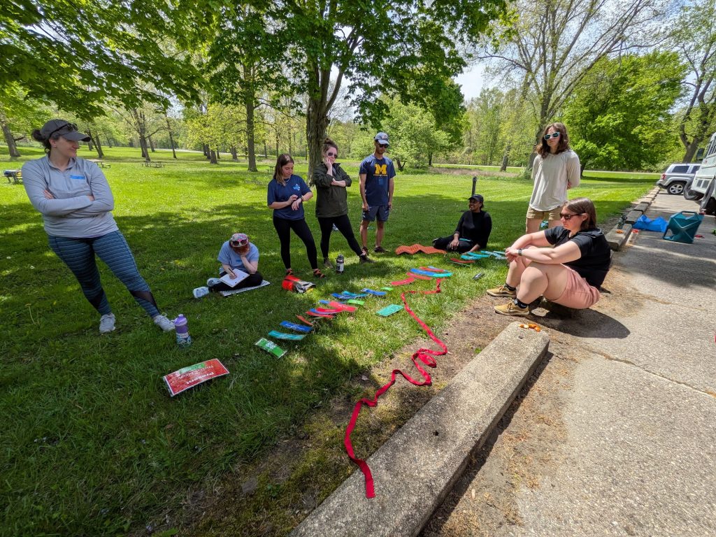 An instructor leads a Leave No Trace principles session with participants gathered on the grass