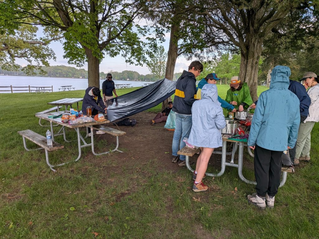 Participants rig a tarp shelter over picnic tables during a hands-on skills session