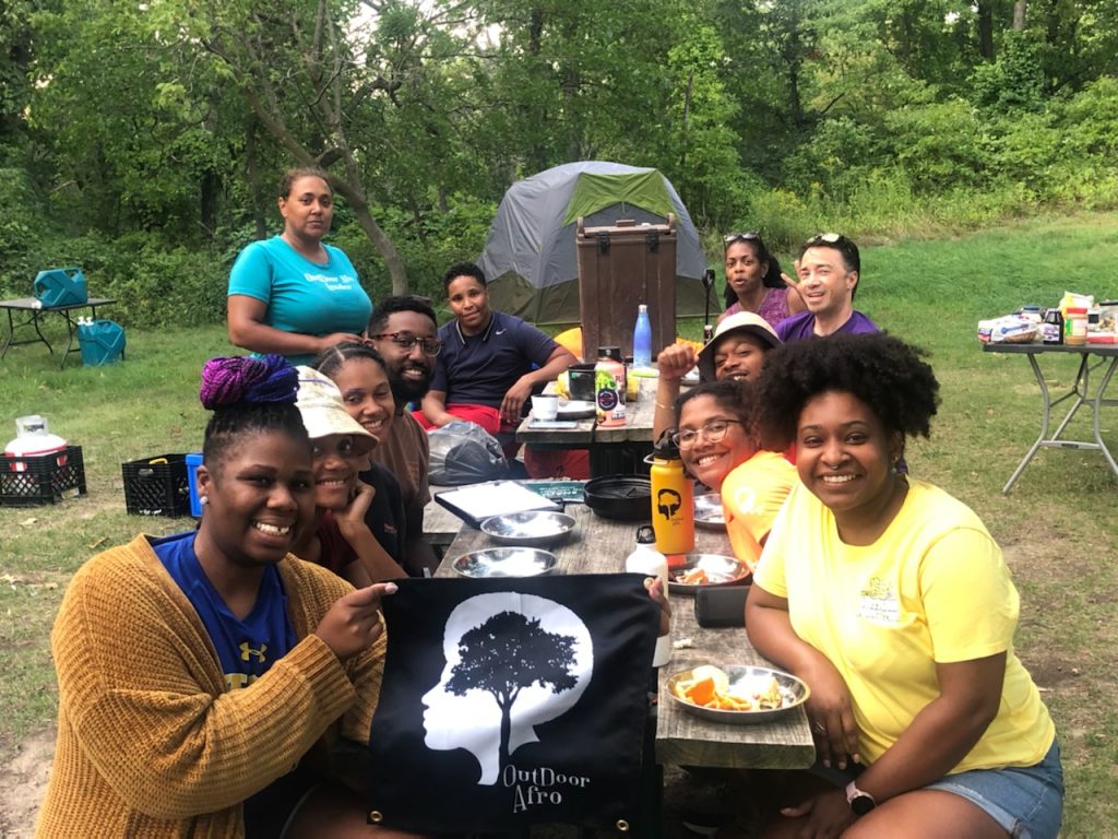 Outdoor Afro participants around a picnic table at Indiana Dunes, holding the Outdoor Afro banner